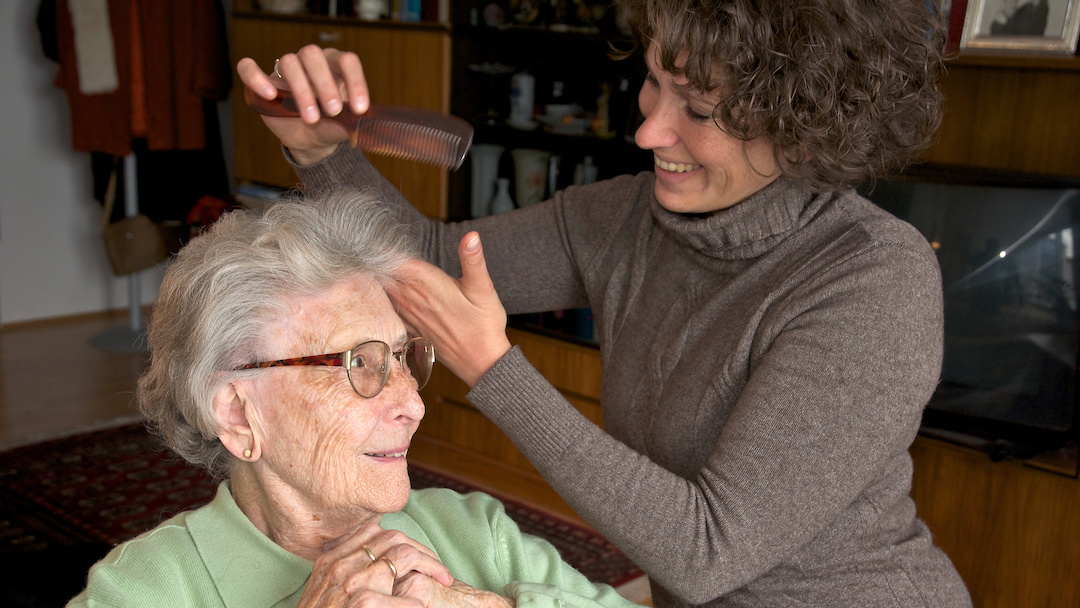 A woman combs an elderly woman's hair as part of a conservatorship